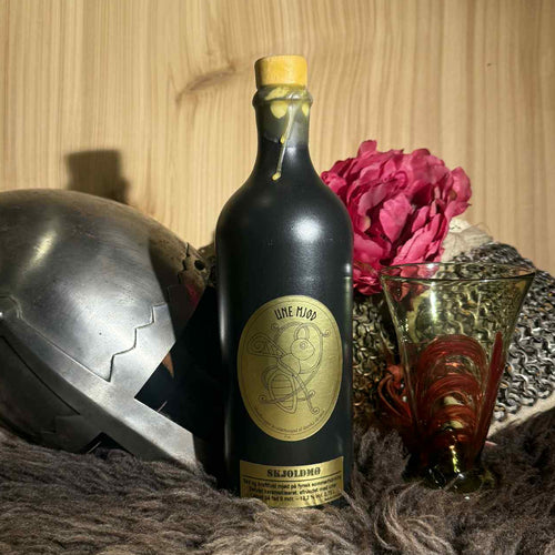 Skjoldmø mjød – sød, mørk og urtekrydret mjød på karamelliseret sensommerhonning. Håndbrygget i sort stentøjsflaske, 13,2 % vol.